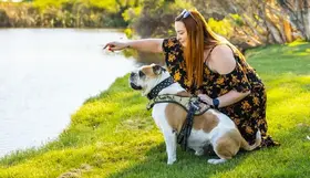 A woman sitting with her dog on grass