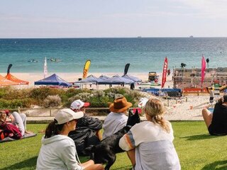 a group of people sitting on grass looking at the beach
