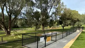 a fenced area with trees and grass