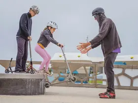 A young person helping a child learn scooter tricks
