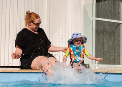 A child and mother splashing in a pool