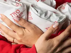 A person holding an armful of Two Slices wrapped sandwiches