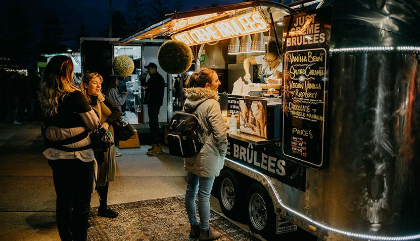 Three women waiting in front of a food truck at the Scarborough Sunset Markets