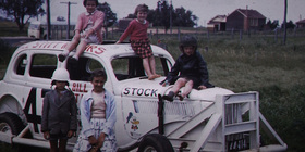 A group of children surrounding a vintage car