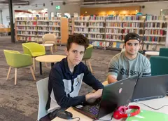 Young people using laptops in a library