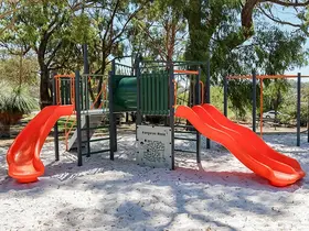 a playground with slides and trees in the background