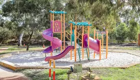 a playground with a purple slide and yellow poles