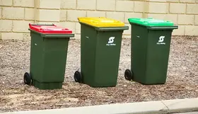 a group of green trash cans with red and yellow lids