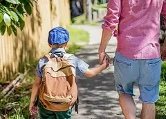 A person walking a child down a street