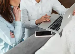 a woman and a child looking at a laptop