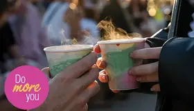 Two people holding steaming cups