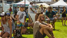 Image of people in the sunshine sitting on the grass at a market