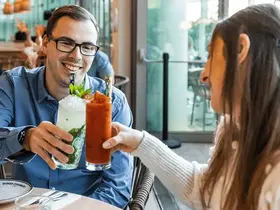 Two people clinking drinks
