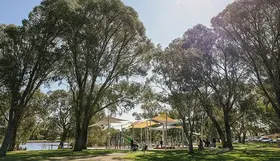 a playground with trees and people on a sunny day