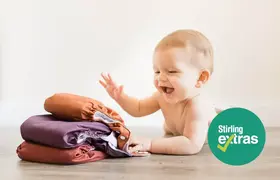 A baby next to a pile of nappies