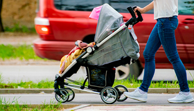 A woman and a child in a pram on a footpath