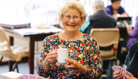 An older Australian holding tea