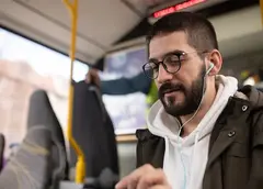 A man using earphones on a bus