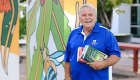 a man holding books in front of a wall