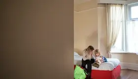 A woman and child sitting on a bed