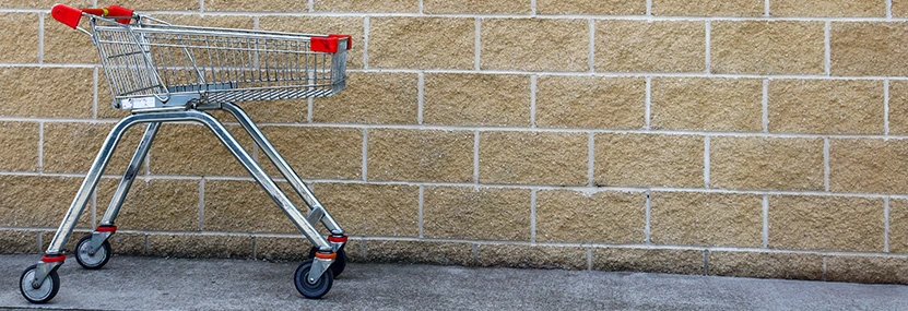 Shopping trolley left abandoned against a brick wall