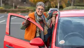 An older Australian standing next to a car