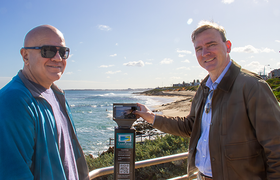 Coastal Ward Councillors Tony Krsticevic and Rob Paparde standing at a coastal lookout beside a CoastSnap monitoring station, with Mettams Pool in the background.