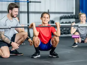 A group of young people learning to lift barbells