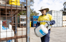 A worker placing a gas container in a cage