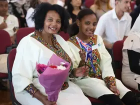 Two women holding flowers and a flag